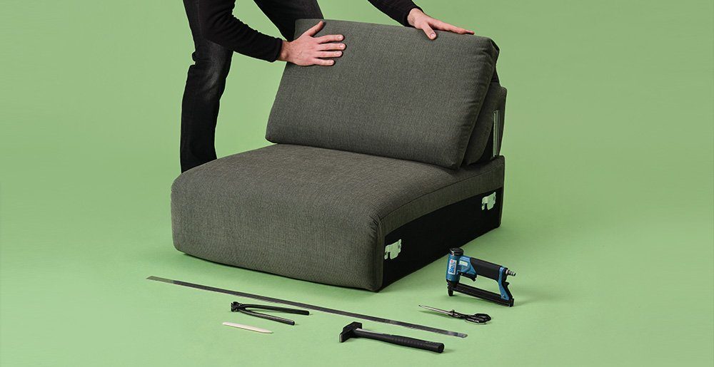 Qualität - Verarbeitung - mobil Ein Sofa-Experte verarbeitet ein Sofasitz mit dem benötigten Werkzeug.